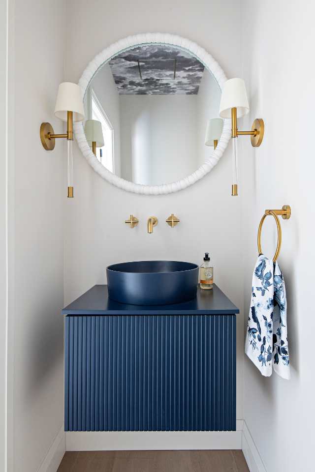 half bath with stunning blue vanity, cloud ceiling, and gold accents